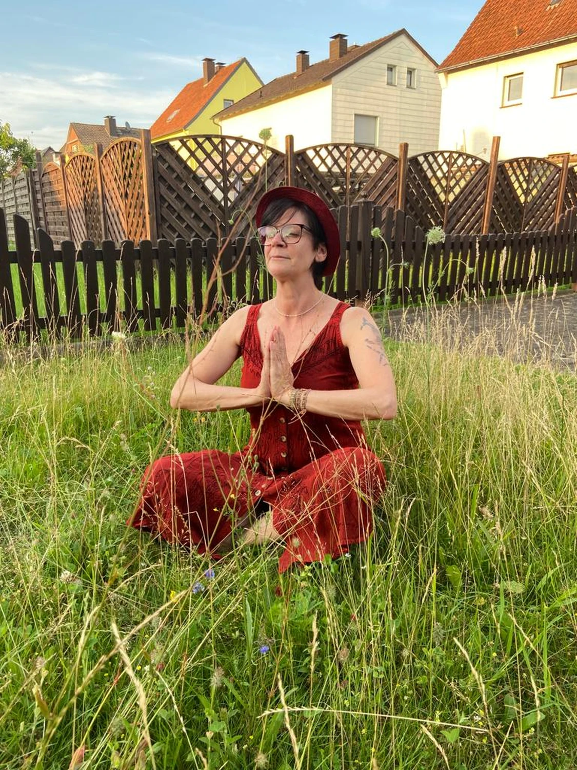 Manuela Möller sitzt in einem Garten und meditiert